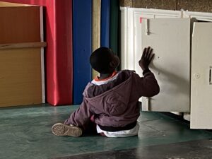 Deafblind boy playing with a cabinet door in a school in Nairobi